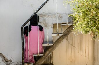 The back of a young woman sitting on a staircase.