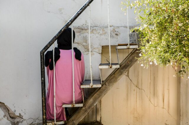 The back of a young woman sitting on a staircase.