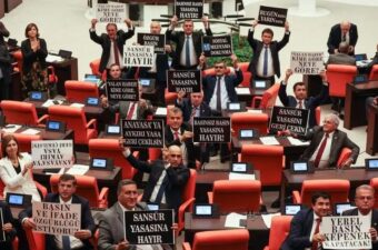 Opposition Republican People's Party deputies hold signs in protest of a government-backed bill that criminalizes "disinformation," at the Grand National Assembly of Turkey in Ankara, October 4, 2022.