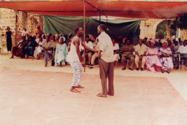 Two men acting out a story in front of an audience in Senegal