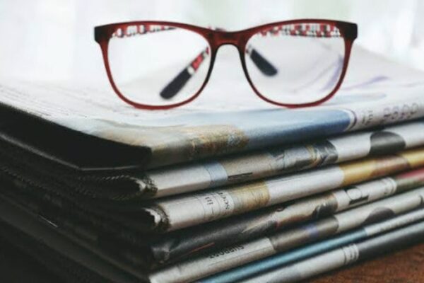 A pair of glasses sitting on top of newspapers