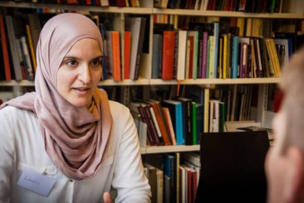 Muslim woman in a library having a conversation with a man.