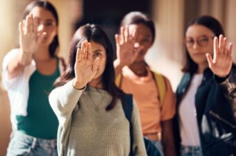 Diverse group of women pictured with a hand up as if to say "stop"