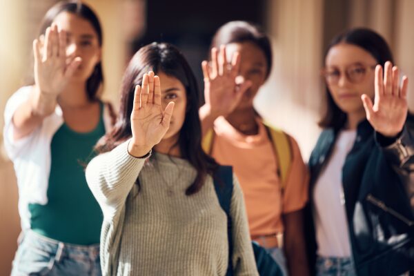 Diverse group of women pictured with a hand up as if to say "stop"