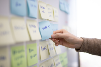 A hand reaching out to grab a post it note, amongst many post its in different languages