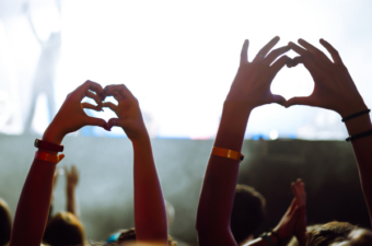 Hands raised forming a heart at a concert