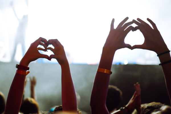 Hands raised forming a heart at a concert