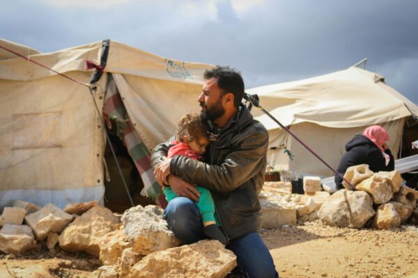 man holding his daughter at a campsite for displaced families