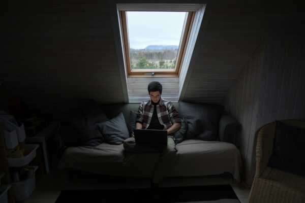 Young man sits in the dark on a computer.