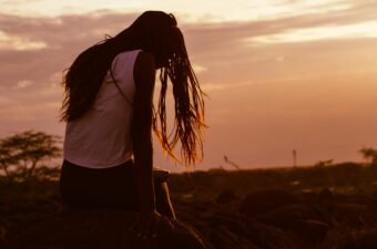 Kenyan Woman Wearing White Sleeveless Top Sitting on Stone