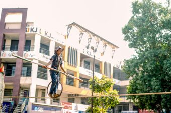 A young boy on a wheel balancing on a rope in India