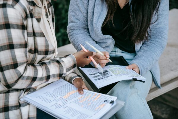 cropped image of two people talking and marking their notes