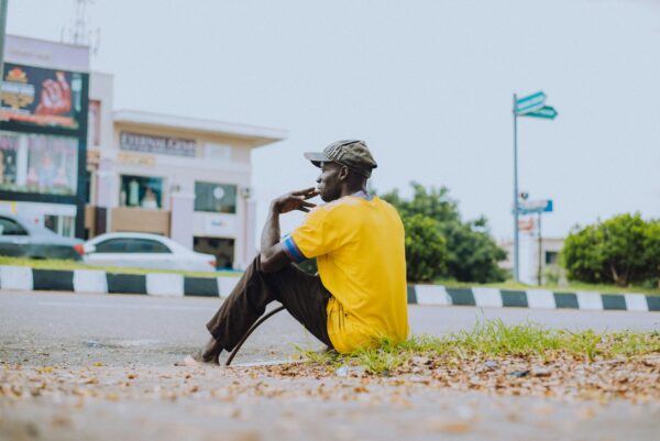 A man sits on the sidewalk alone in an African country