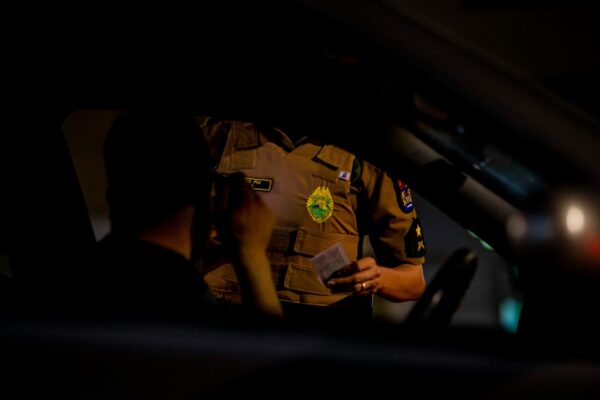 Cropped photo of a Brazilian police officer at the car window of a citizen