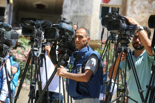 camera operators standing behind their cameras in Gaza