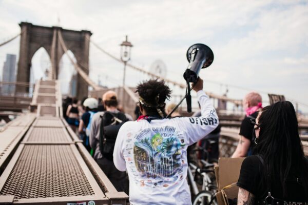 A protestor holds a megaphone in front of a bridge