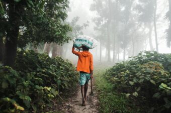 A man walking down a path in the fog with an umbrella (in rural Bangladesh)