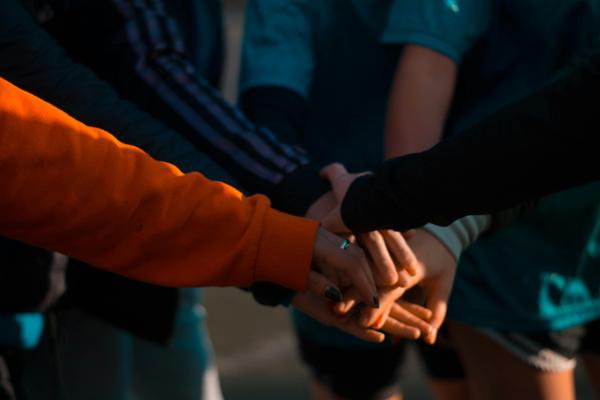 Close-up of a group of people placing their hands together in a show of unity and solidarity