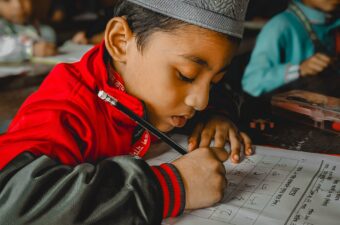 A school boy sitting at a desk writing in Bangladesh