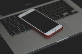 Phone with a black screen sitting on top of a computer.