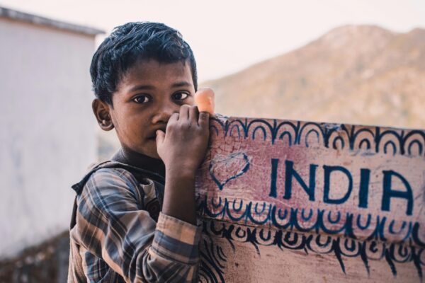 Close-Up Photography Of A Boy Near A Signboard that says India