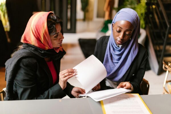 Two women in head scarves reviewing documents together