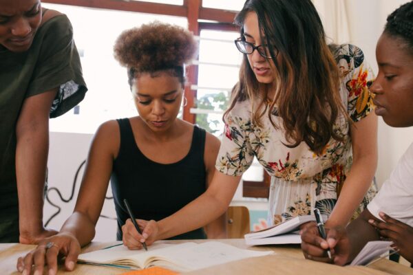 People gathered at a desk, two women explaining something