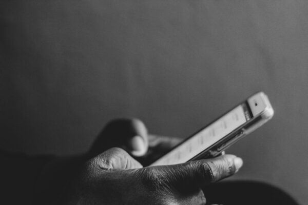 Black and white photo of hands holding a mobile phone as if texting