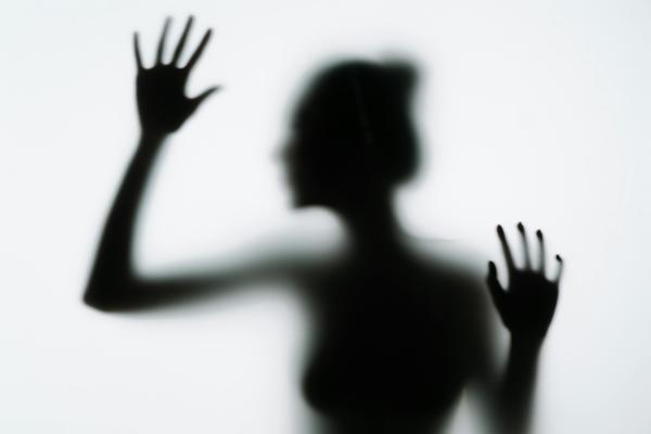 Silhouette of a person with hands pressed against frosted glass