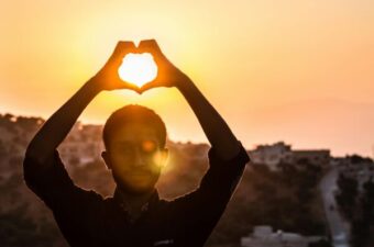 Person Making Heart Shape With His Hand During Sunset