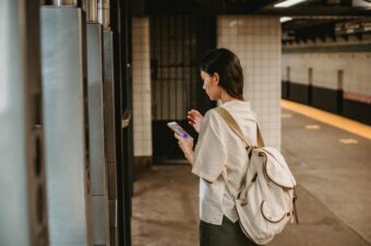 A woman at a train station looking at her smartphone.