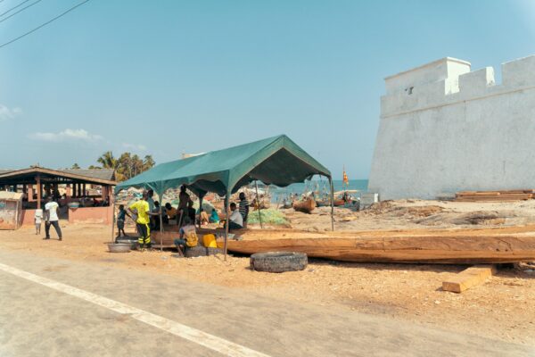 People under a green tent at a beach in Ghana