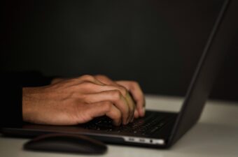 Hands typing on a laptop over a dark background