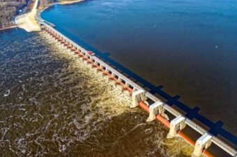 An aerial view of a dam structure on a large body of water, showcasing water flow and engineering infrastructure.