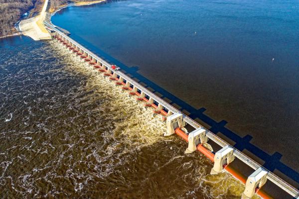 An aerial view of a dam structure on a large body of water, showcasing water flow and engineering infrastructure.