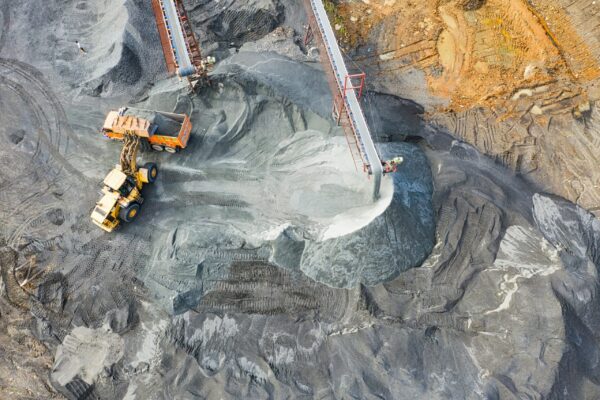 Aerial view of extractive mining site with trucks gathering resources into a truck.