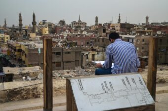 Man Sitting against Cityscape of Cairo