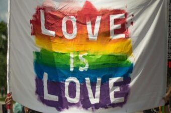 Banner with a colorful rainbow background reading 'Love is Love,' symbolizing LGBTQ+ pride and inclusivity.