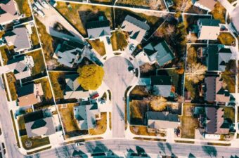 An aerial view of a suburban neighborhood with houses arranged, showcasing organized homes, lawns, and roads.