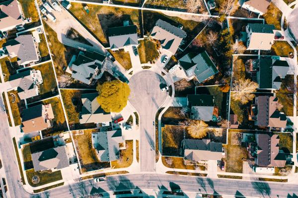 An aerial view of a suburban neighborhood with houses arranged, showcasing organized homes, lawns, and roads.