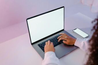 Person typing on a laptop with a blank screen