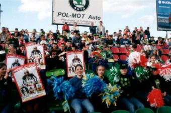 Let’s Kick Racism Out of the Stadium poster featuring Polish soccer player Emmanual Olilsadebe, a group of kids displaying the poster during an international soccer match